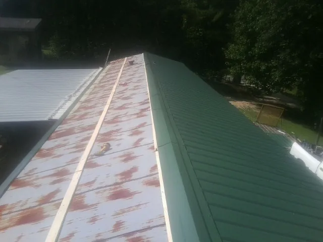 Old rusted panels beside newly installed green metal roofing — Wind Damage Roof Repair by Roofing Brothers in Pocasset