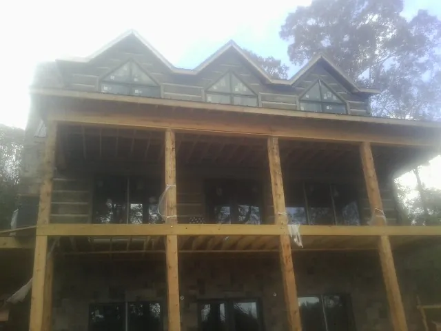 Dormers and porch framing on a large log home under construction — Roof Coating work by our crew in Pocasset