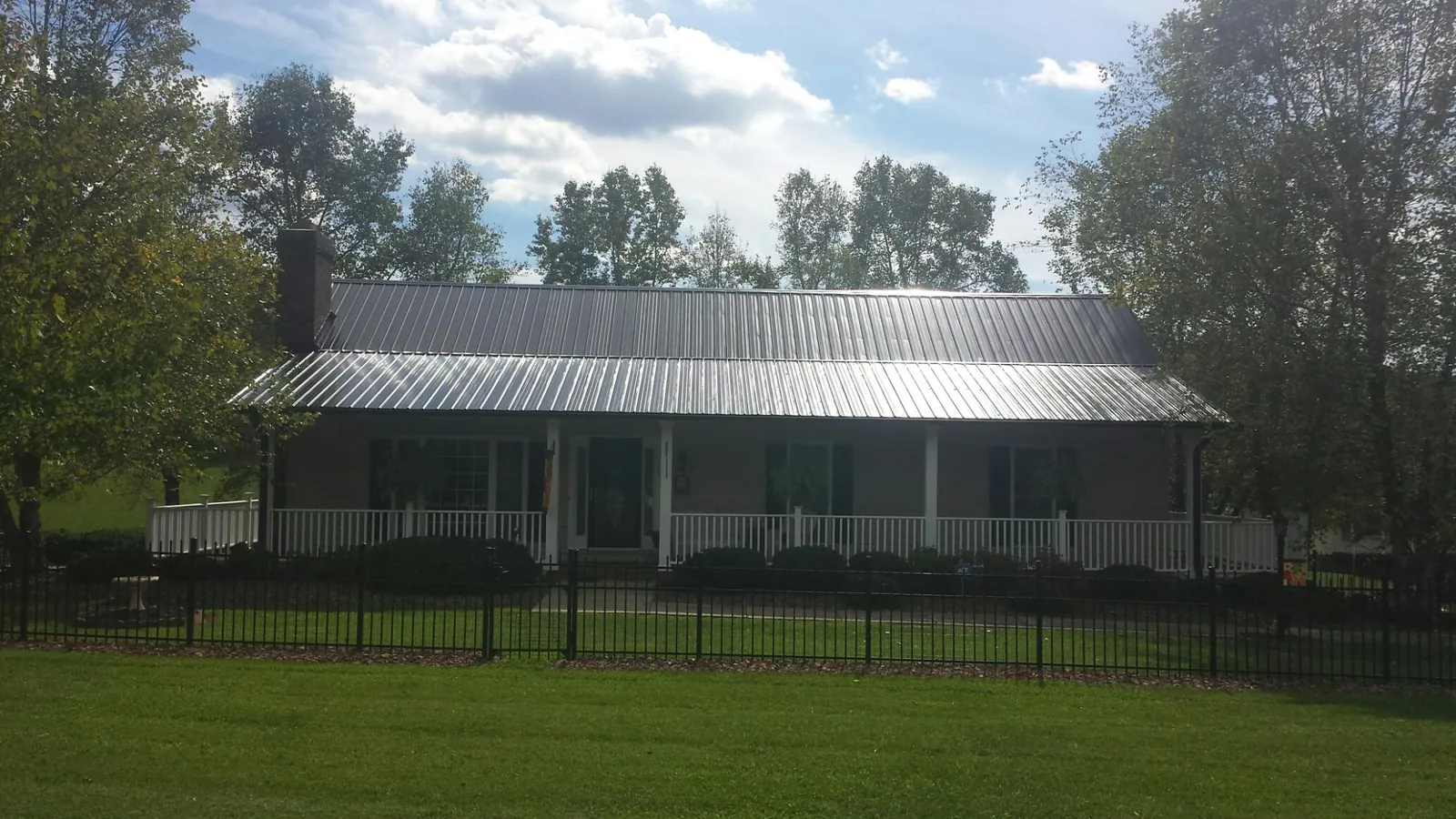 Gray metal roof on a brick ranch with a full width front porch — Gutter Guard Installation work by our crew in Pocasset