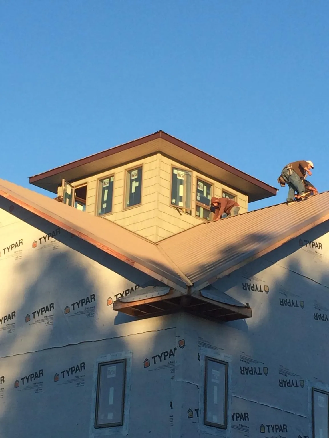 Roofers working around a rooftop cupola on a new metal roof at sunset — Roof Waterproofing in Pocasset by Roofing Brothers
